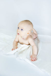 Portrait of cute baby boy lying on bed at home