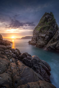 Rocks on shore against sky during sunset