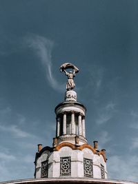 Low angle view of statue by building against sky