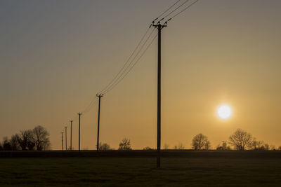 Electricity pylon on field against sky during sunset