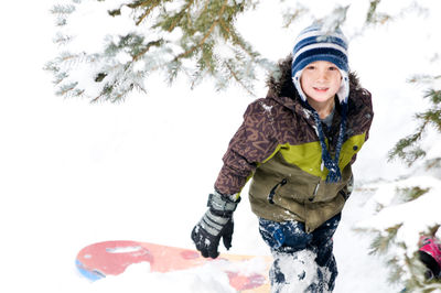 Portrait of smiling boy wearing warm clothing while walking in snow