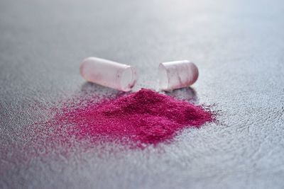 Shiny pink powder spilled from open capsule on table