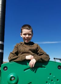 Portrait of happy boy playing against blue sky