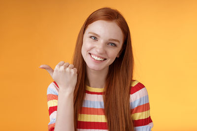 Portrait of smiling young woman against yellow background