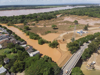 River flooding due to rain causes large mud next to a dam that prevents the rivers from meeting 