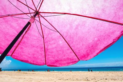 Pink umbrella on beach against clear sky