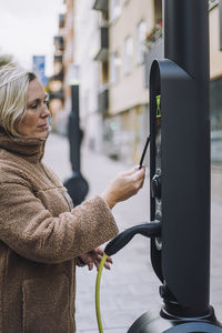 Mature woman paying via digital wallet at electric vehicle charging station