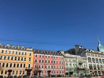 Low angle view of buildings in city against clear blue sky