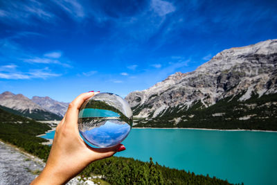 Cropped hand holding crystal ball against mountain