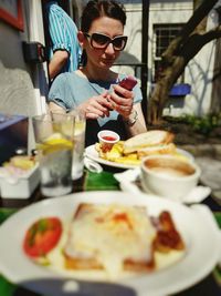 Close-up of food on table by woman using smart phone