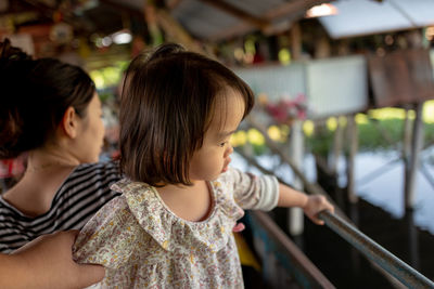 Cropped hand of mother holding toddler daughter in restaurant over lake