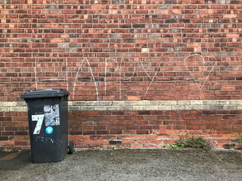 Garbage bin against brick wall