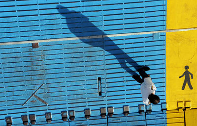 Directly above shot of man walking on blue walkway during sunny day