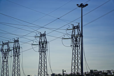 Low angle view of silhouette electricity pylon against sky