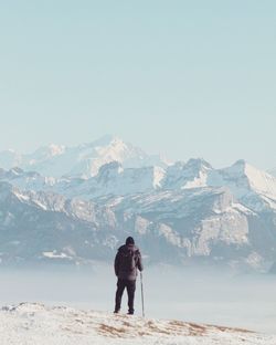 Rear view of man standing on snow covered mountain