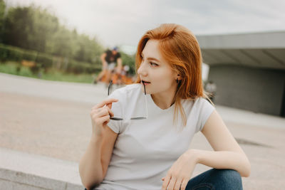 Young woman looking away while sitting outdoors