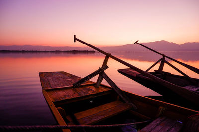 Fishing boat moored in sea against sky during sunset