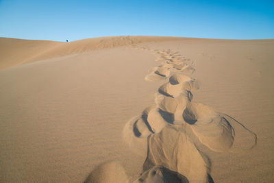 Sand dunes in desert against clear sky