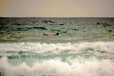 Man swimming in sea against clear sky