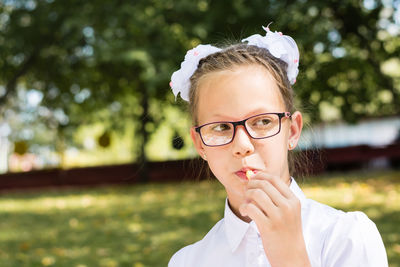 Cute little school girl wearing glasses eats french fries on a picnic in the park. school meals