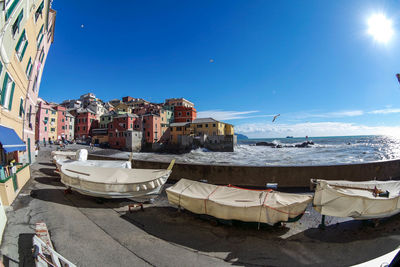 Sailboats moored on sea by buildings in city against sky