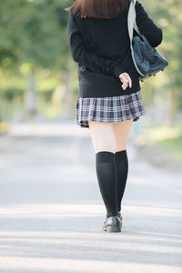 Low section of woman standing on road