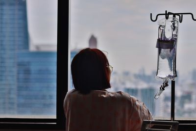 Rear view of man looking through window