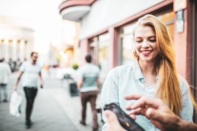 Portrait of smiling young woman using mobile phone in city