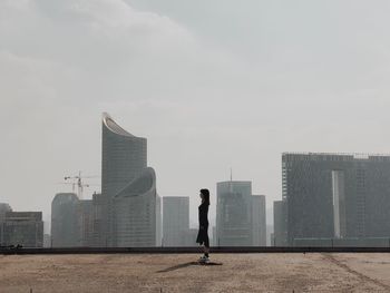 Man standing by modern cityscape against sky