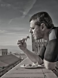 Portrait of man holding ice cream against sky