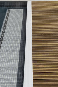 Background and texture of swimming pool area with wooden flooring and blue tiling for summer time