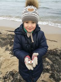 High angle portrait of girl holding clam while standing at beach during winter