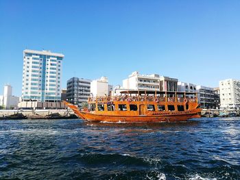 Boats in sea against clear blue sky