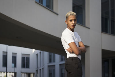 Portrait of young man standing against building