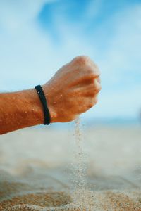 Cropped hand of man holding sand at beach