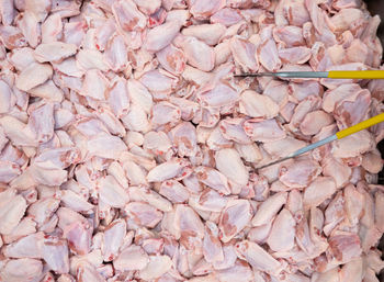 Fresh chicken middle wings in the metal tray with food tongs for sale in the market.