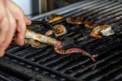 Cropped hand preparing food on barbecue grill