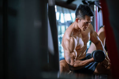 Midsection of shirtless man with arms raised