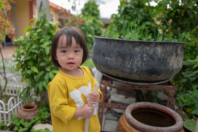 Portrait of cute baby girl holding garden house while standing in yard