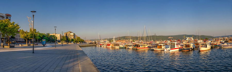 Sailboats in marina at harbor against clear sky