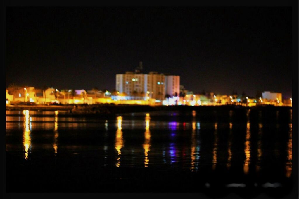 illuminated, night, building exterior, architecture, water, reflection, built structure, waterfront, city, river, clear sky, cityscape, copy space, sky, lake, building, dark, outdoors, residential building, city life