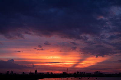 Scenic view of dramatic sky over city during sunset