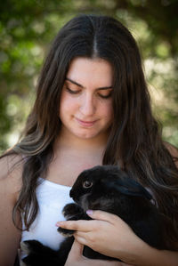 Young beautiful woman holding a black rabbit pet animal. domestic animal caring