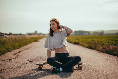 Portrait of young woman sitting on skateboard