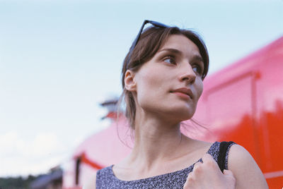 Low angle view of thoughtful young woman looking away against clear sky