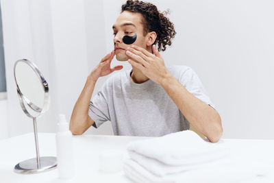 Young woman using mobile phone while lying on bed at home