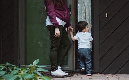 Low section of woman with son standing at doorway