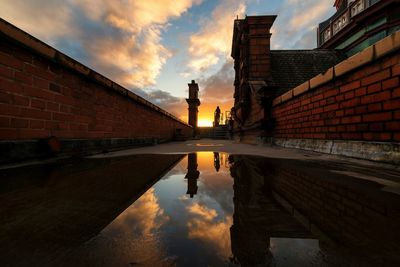 Reflection of building on puddle during sunset