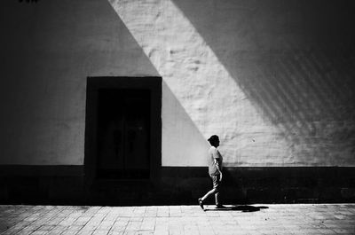 Full length of woman walking in front of wall