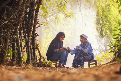 Asian muslim dress sitting reading quran books of islam and the brother in the bamboo forest.